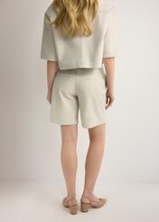 Dámske krémové kožené šortky SPODS-0047-0B(W26), pohľad na modelku zozadu. Viditeľná polovica siluety.