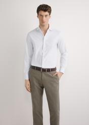 Pánska biela bavlnená košeľa KOSMT-0358-0A(W26) - pohľad spredu na produkt, na modelke, na svetlom pozadí. Viditeľná silueta po pás.