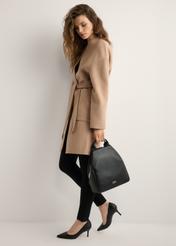 Čierny dámsky batoh z imitácie kože TOREC-0923-99(W26), pohľad na produkt v ruke modelky. Viditeľné celé telo.