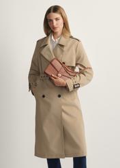 Dámska hnedá taška cez rameno TOREC-1137-1F(W26) - pohľad spredu na produkt, na modelke, na svetlom pozadí. Viditeľná silueta po kolená.