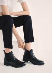 Dámske čierne kožené krátke Chelsea čižmy BUTYD-1116-99(Z25), pohľad na produkt na nohách modelky na svetlom pozadí.