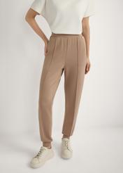 Karamelové zúžené nohavice SPODT-0104 A-1D(W26), pohľad spredu na výrobok na modelke. Viditeľná polovica siluety.