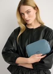 Modrá malá dámska kabelka TOREC-1172-7C(W26), pohľad na produkt v ruke modelky. Viditeľná polovica siluety.