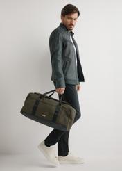 Kaki cestovná taška TORMN-0417-8D(W26) - pohľad spredu na produkt, ktorý drží modelka, na svetlom pozadí.