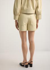 Svetložlté dámske kožené šortky SPODS-0035-2A(W26), pohľad na produkt zozadu na modelke, viditeľná polovica siluety.