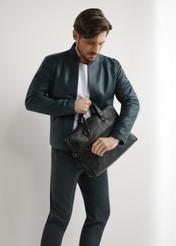 Čierna kožená taška na notebook TORMS-0496-99(W26) - diagonálny pohľad na produkt, ktorý drží modelka, na svetlom pozadí. Viditeľná je celá silueta.