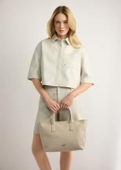 Krémová dámska kabelka s vrkočom TOREC-1212-0B(W26) - pohľad spredu na produkt, ktorý drží modelka v ruke, na svetlom pozadí.