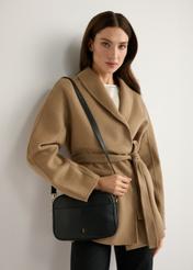 Malá čierna kožená dámska kabelka TORES-1284-9I(W26) - pohľad spredu na produkt, na modelke, na svetlom pozadí. Viditeľná silueta po polovičnú dĺžku.