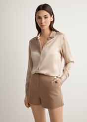 Dámske elegantné šortky v ťavej farbe SZODT-0018-1D(W26), pohľad spredu na produkt na modelke. Viditeľná polovica siluety.