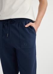 Pánske tmavomodré tepláky SPOMT-0109-69(W25) - detailný záber na predný detail modelu na bielom pozadí.