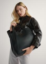 Dámska čierna kožená nákupná kabelka TORES-1208-9I(W26) - pohľad na produkt držaný v ruke modelky na svetlom pozadí. Viditeľná je polovica siluety.