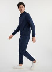 Pánske tepláky v tmavomodrej farbe SPOMT-0109-69(W25) - bočný pohľad na modelku na bielom pozadí. Celá silueta je viditeľná.