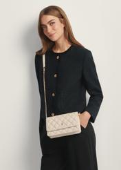 Krémová malá prešívaná dámska kabelka TOREC-1033-0B(W26), pohľad na produkt na ramene modelky. Viditeľná polovica siluety.