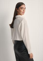 Dámska biela bavlnená košeľa KOSDT-0181-0A(W26), pohľad na produkt zozadu na modelke, viditeľná polovica siluety.