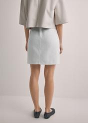 Krémová džínsová minisukňa SPCDT-0126-0B(W26), pohľad zozadu na produkt na modelke. Viditeľná polovica siluety.