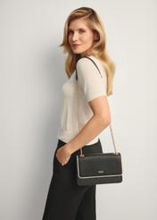 Malá čierna dámska kabelka TOREC-1015-9J(W26), pohľad spredu na produkt na modelke, viditeľná polovica siluety.