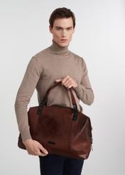 Veľká pánska hnedá kožená taška TORMS-0103-1H(W26), pohľad na produkt v rukách modelky, na svetlom pozadí.