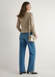 Dámska krémová kabelka cez rameno TOREC-1120-0P(W26) - pohľad na produkt mierne diagonálny, na modelke, na svetlom pozadí. Viditeľná je celá silueta.