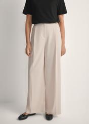 Svetlobéžové dámske nohavice SPODT-0119-1A(W26), pohľad spredu na výrobok na modelke. Viditeľná polovica siluety.