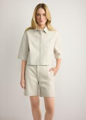 Dámske krémové kožené šortky SPODS-0047-0B(W26), pohľad spredu na produkt na modelke. Viditeľná polovica siluety.