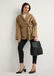 Čierny stredne veľký dámsky batoh TOREC-1132-99(W26) - pohľad spredu na produkt, ktorý drží modelka, na svetlom pozadí. Viditeľná je celá silueta.