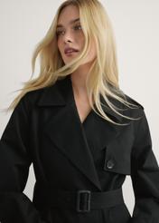 Dlhá čierna dámska bunda v podobe kabáta KURDT-0512-99(W25), pohľad na produkt spredu na modelke, viditeľná polovica siluety.