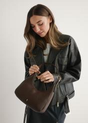 Malá hnedá dámska kabelka TOREC-1239-1I(W26) - pohľad spredu na produkt, ktorý drží modelka, na svetlom pozadí. Viditeľná je polovica siluety.