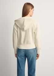 Dámska krémová mikina s kapucňou BLZDT-0113-12(Z25), pohľad na produkt zozadu na modelke, viditeľná polovica siluety.