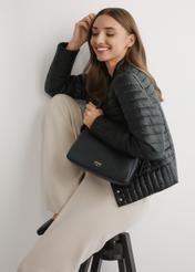 Čierna kožená dámska kabelka TORES-1277-9I(W26) - pohľad spredu na produkt, na modelke, na svetlom pozadí. Viditeľná silueta po polovičnú dĺžku.