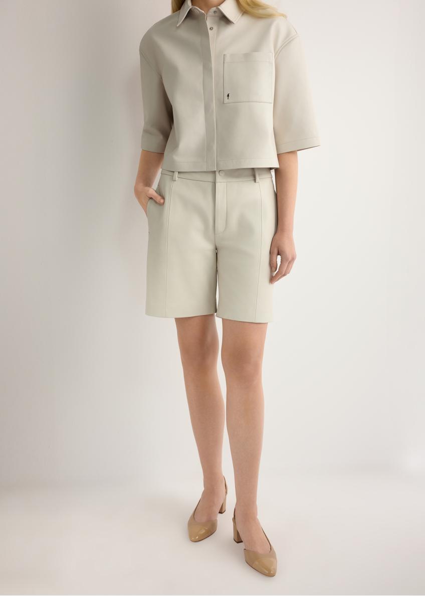 Dámske krémové kožené šortky SPODS-0047-0B(W26), pohľad spredu na produkt na modelke. Viditeľná polovica siluety.