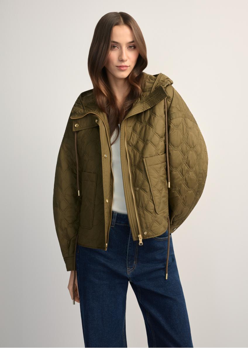 Olivovozelená krátka prešívaná oversize bunda KURDT-0660-8D(W26) - pohľad spredu na výrobok, na modelke, na svetlom pozadí. Viditeľná polovica siluety.