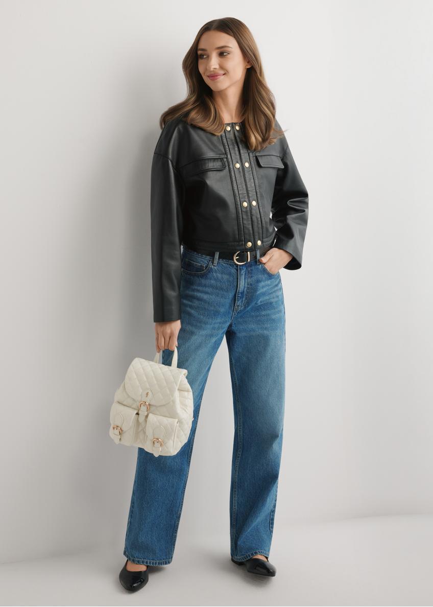 Dámsky prešívaný batoh TOREC-1195-0A(W26) v krémovej farbe - pohľad spredu na produkt, ktorý drží modelka, na svetlom pozadí. Viditeľná je celá silueta.