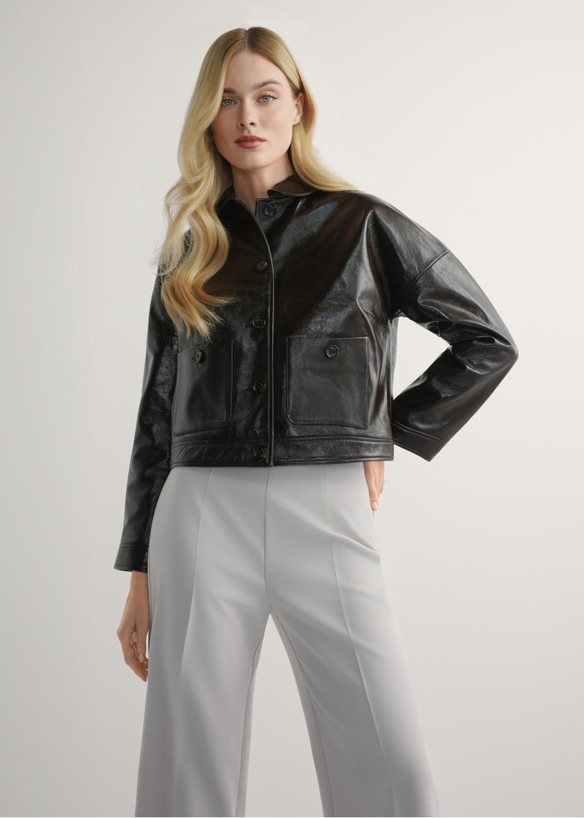 Dámska hnedá krátka kožená bunda KURDS-0593-1I(W26) - pohľad spredu na výrobok, na modelke, na svetlom pozadí. Viditeľná silueta po kolená.