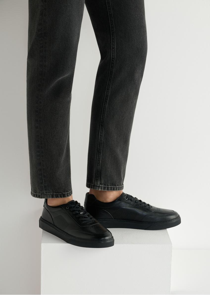 Čierne kožené pánske športové topánky BUTYM-0484-99(W25), bočný pohľad na produkt na modeli, viditeľná polovica siluety.