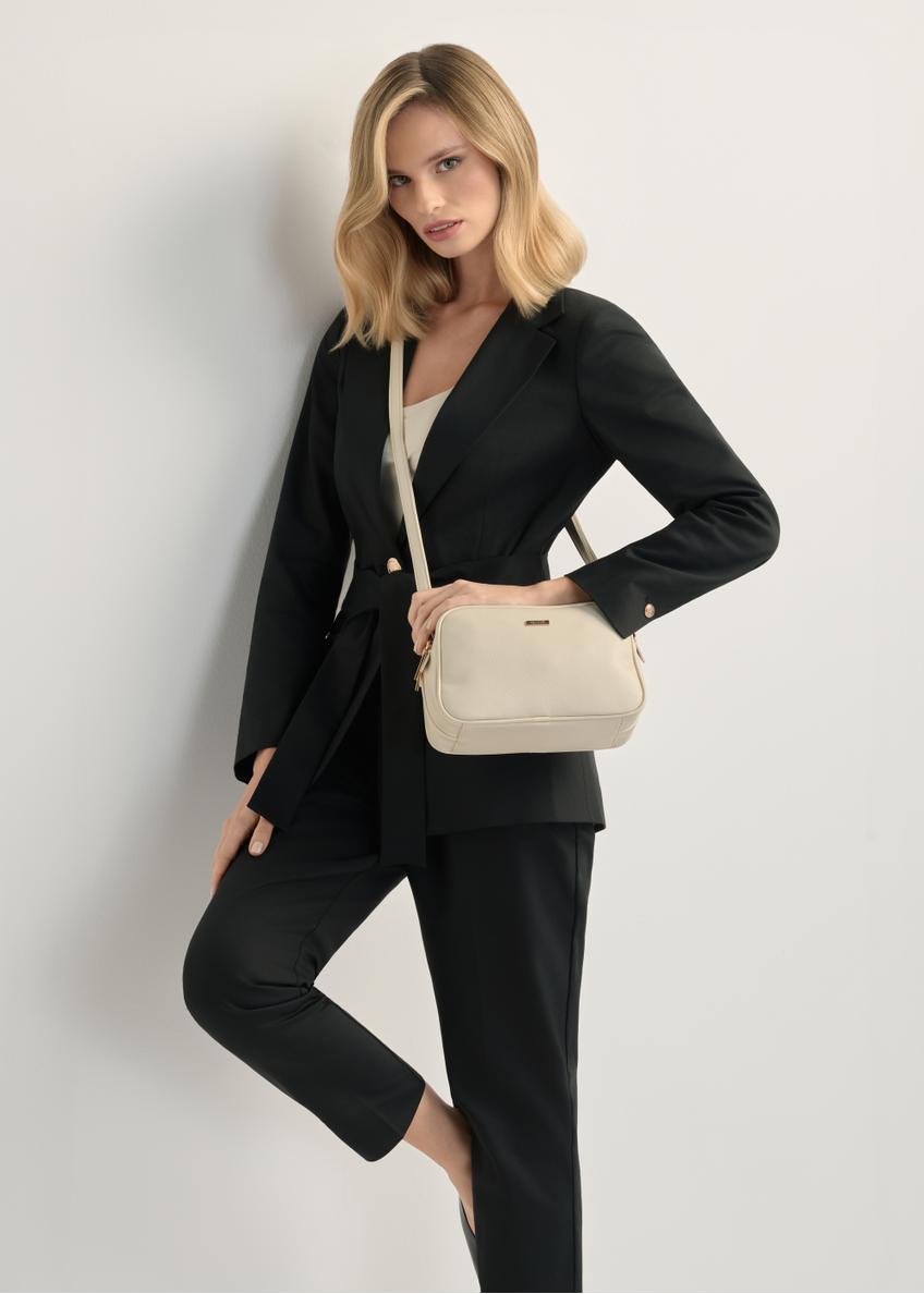 Dámska kabelka strednej veľkosti krémovej farby TOREC-1121-0B(W26), pohľad na produkt na ramene modelky. Viditeľná polovica siluety.