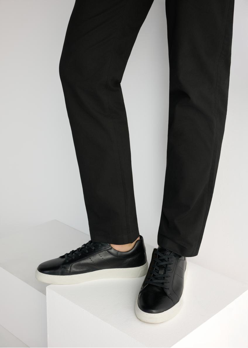 Čierne pánske kožené tenisky BUTYM-0486-99(W26), bočný pohľad na produkt na modeli, viditeľná polovica siluety.