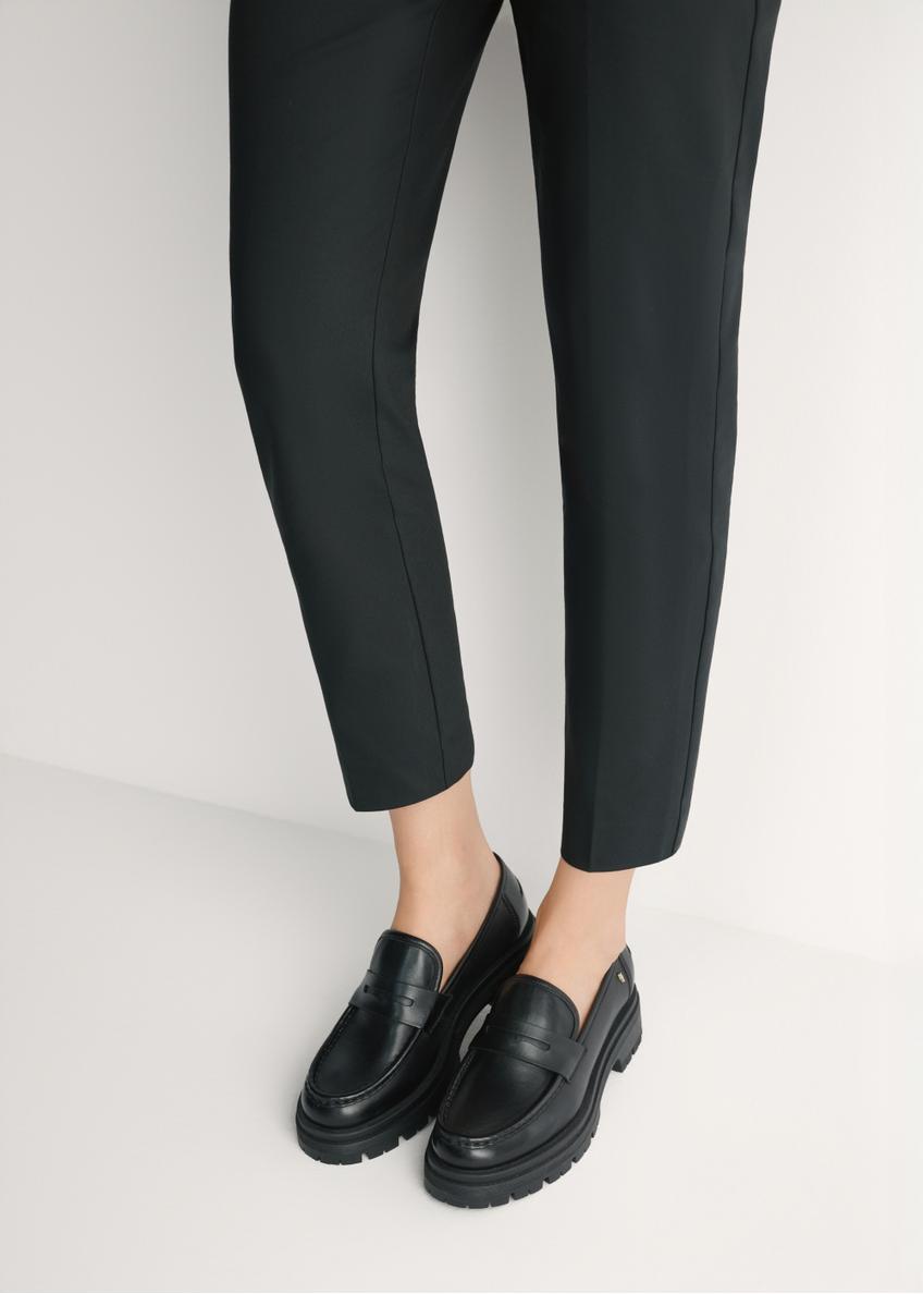 Dámske čierne kožené mokasíny BUTYD-1069-99(W26) - pohľad spredu na výrobok, na modelke, na svetlom pozadí. Viditeľná silueta po kolená.