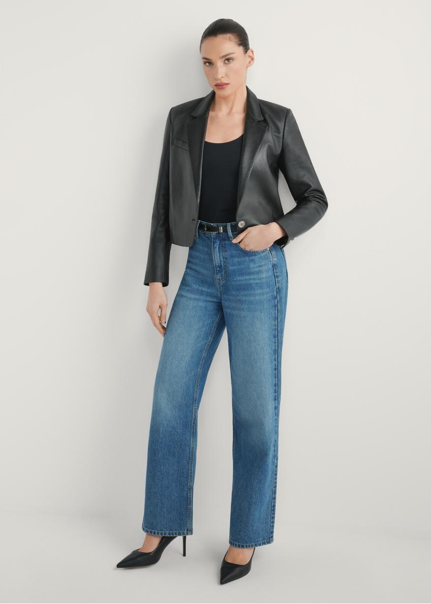 Dámska krátka kožená bunda KURDT-0522-99(W26) - pohľad spredu na výrobok, na modelke, na svetlom pozadí. Viditeľné celé telo.