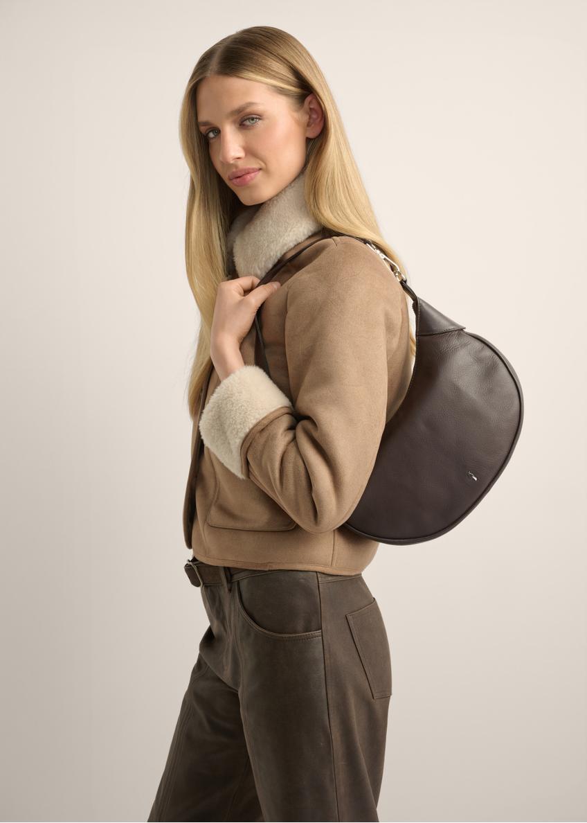 TORES-1318-1H(Z26), polkruhová hnedá dámska kabelka cez rameno. Pohľad na produkt spredu na modelke. Viditeľná polovica siluety.