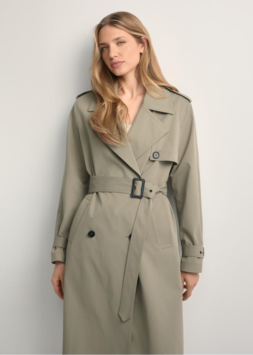 Dámsky kabát dlhej farby šalvie KURDT-0512-8F(W26), pohľad spredu na výrobok na modelke. Viditeľná polovica siluety.